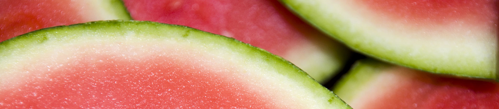 Close up of watermelon slices, you only see the top with a green border and then white and then the red flesh